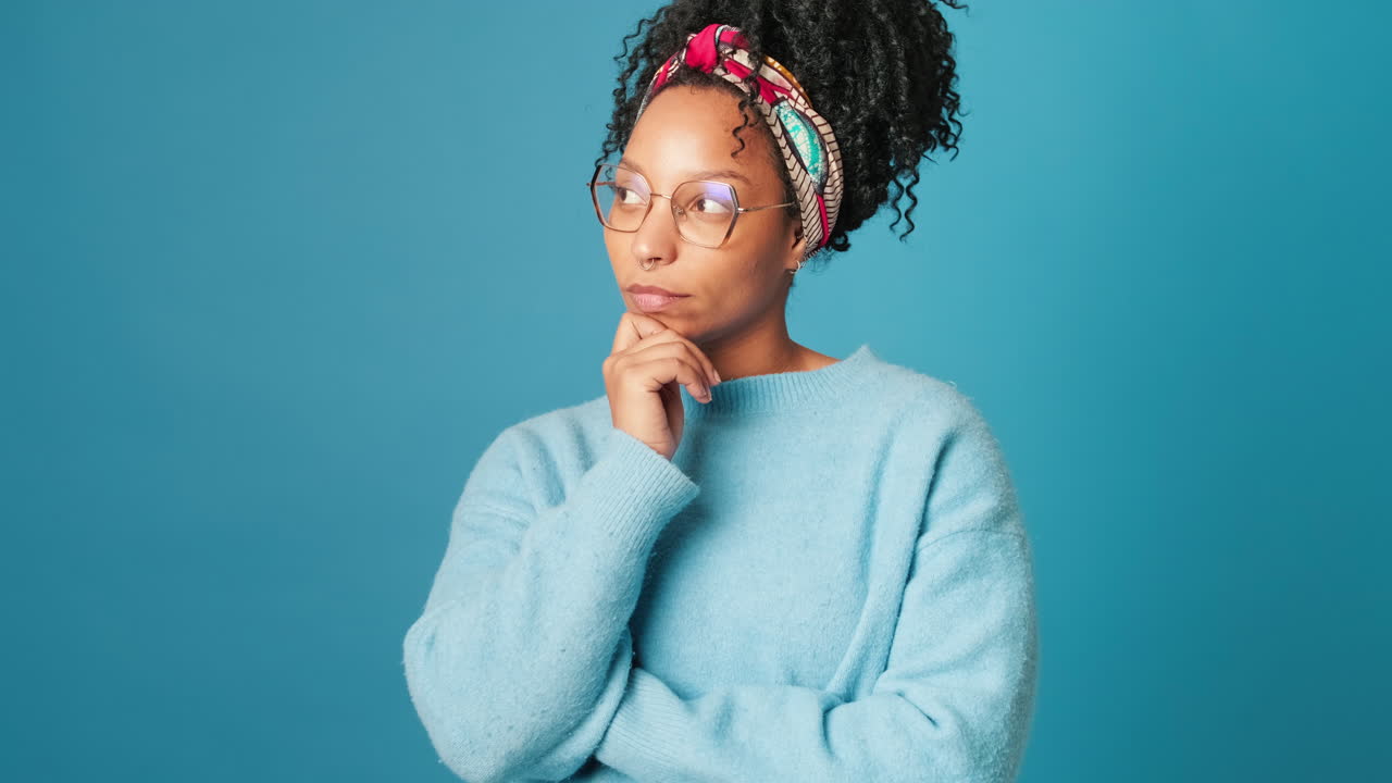 Pensive Young Woman in Glasses Thinking on Blue Background