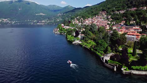 aerial orbit small boat cruising past torno on lake como, italy