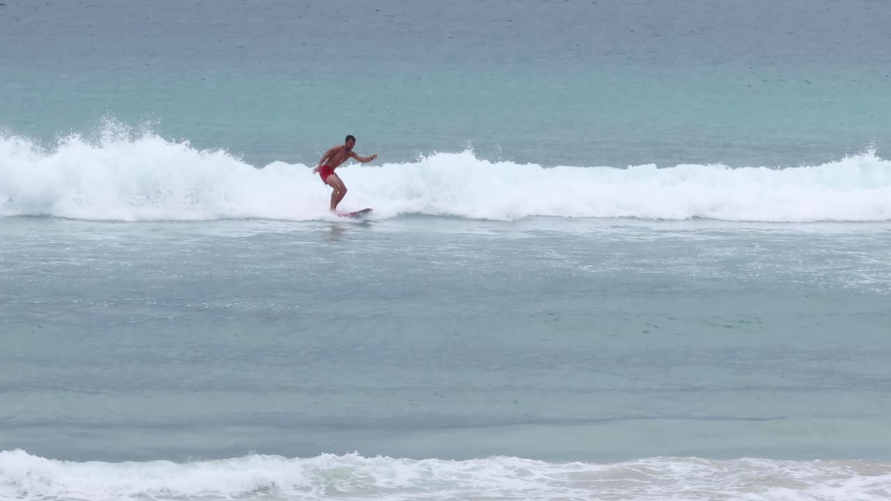A surfer expertly rides the ocean waves, showcasing balance and skill on a surfboard.