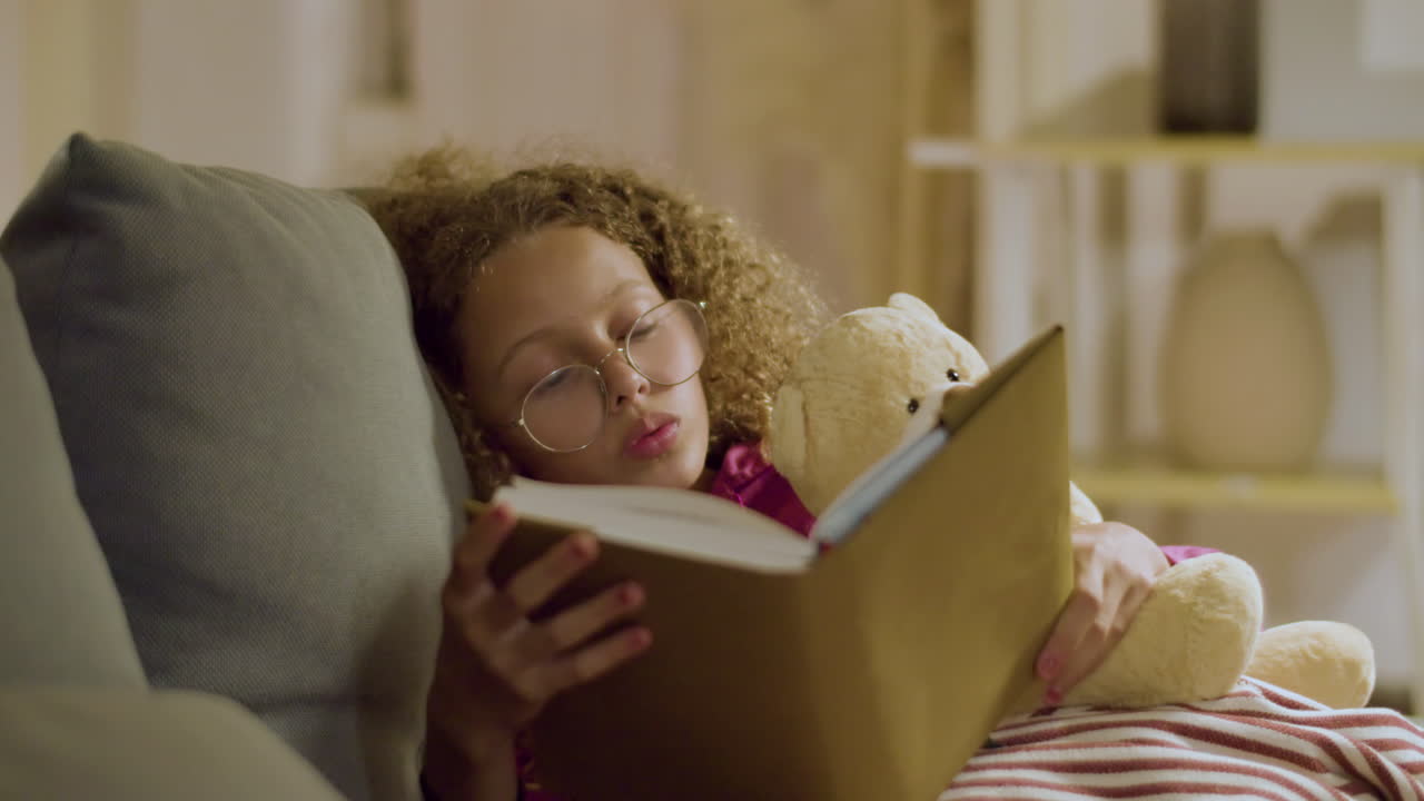 Pretty girl reading interesting stories before falling asleep