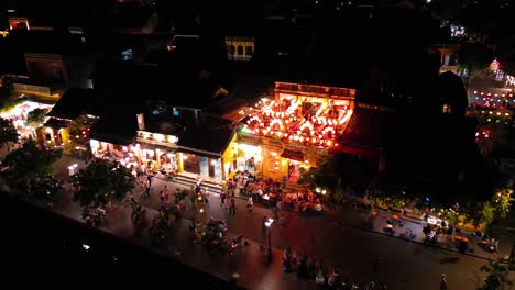 nightlife in hoi an, vietnam. people walk by illuminated restaurants and shops. drone view.