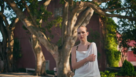 modelo sensual posando parque en ropa blanca. mujer seria mirando a la cámara sola