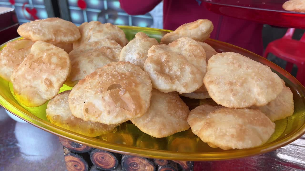 kachoris recién preparados en un plato amarillo en exhibición en la tienda.