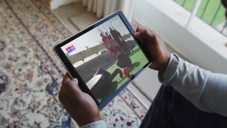 compuesto de un hombre sentado en casa viendo un partido de hockey en una tableta