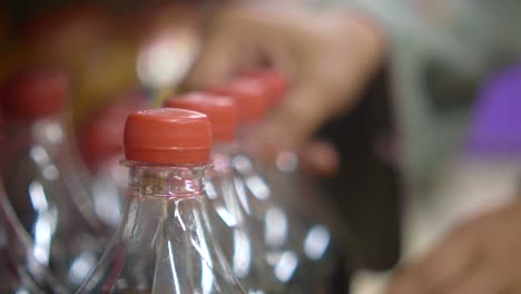 a hand reaching for bottles of soda in a grocery store