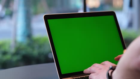 hands using green screen laptop computer on table.