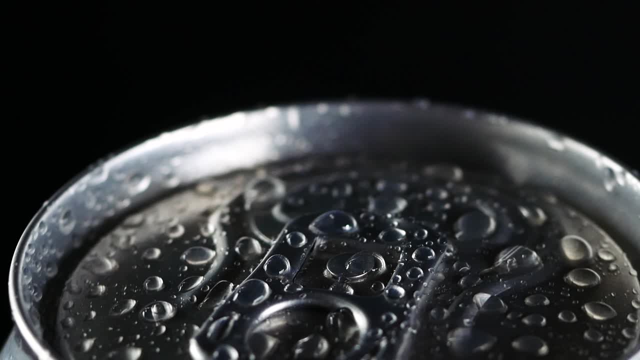 차가운 음료가 검은 바탕에 회전합니다. 소다 또는 맥주 알루미 캔에 물방울이