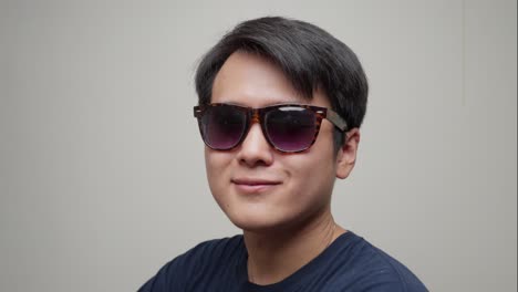 chinese man putting on his glasses against a white background