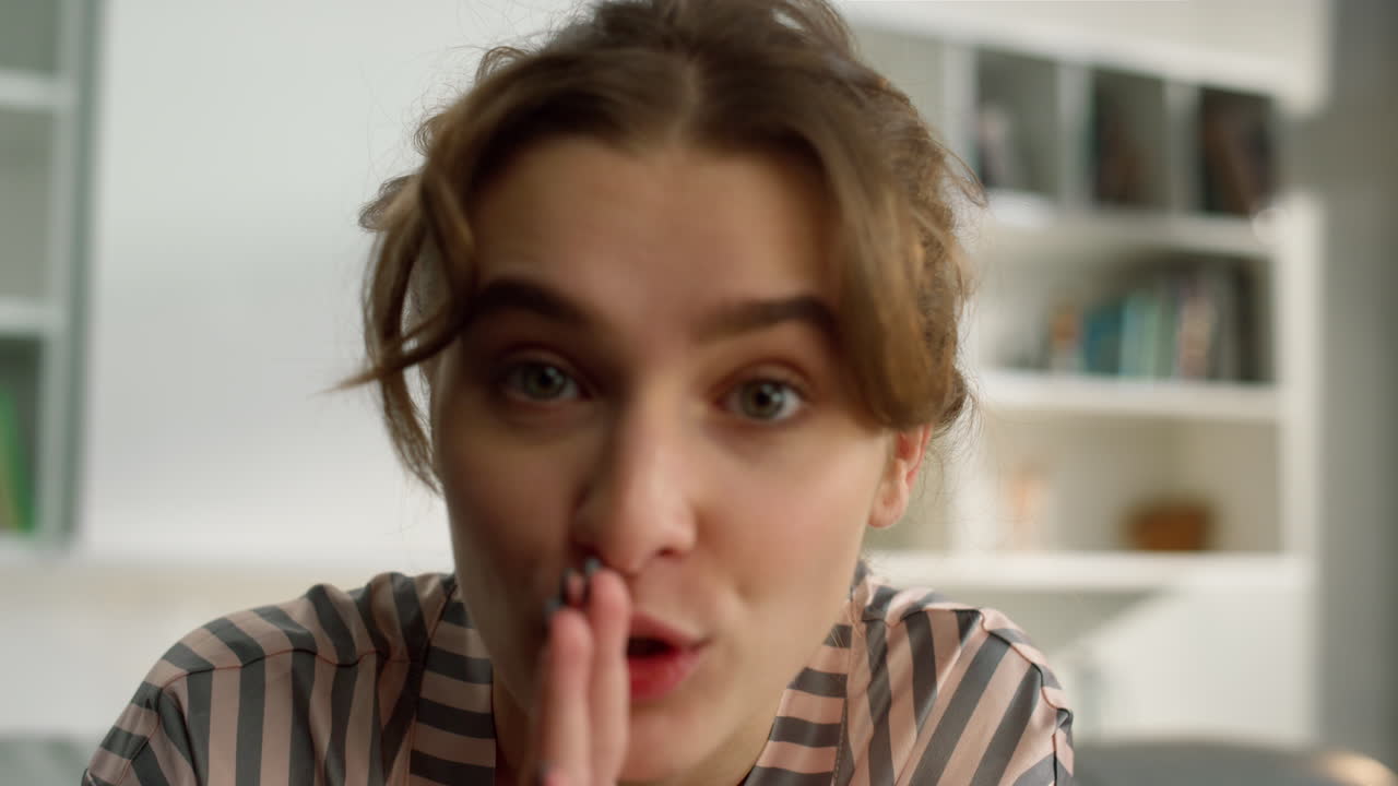 chica bonita compartiendo en línea haciendo un gesto de silencio en la mañana sala de estar de cerca