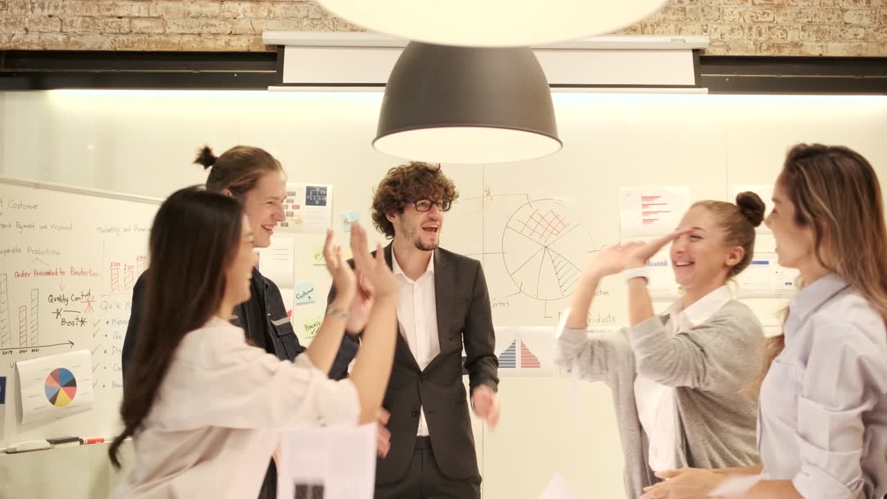 Coworker's team celebrates business success by throwing papers in a meeting.