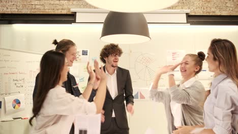 coworker's team celebrates business success by throwing papers in a meeting.