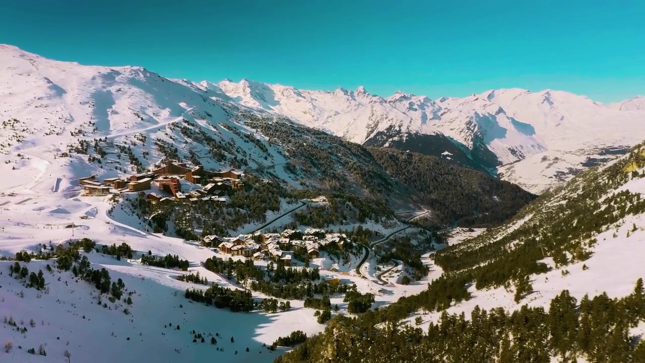 Una vista aerea mozzafiato, cinematografica e ampia che cattura la vasta stazione sciistica di Les Arcs, immersa tra le cime e le valli incontaminate e coperte di neve delle Alpi della Savoia in Francia.