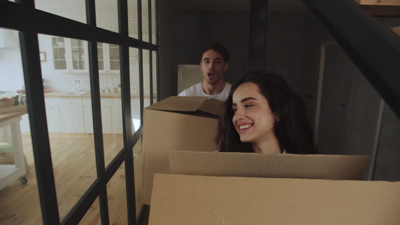 una pareja feliz trayendo cajas de papel a una casa de lujo.