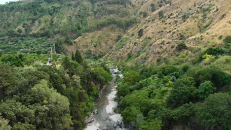 4K-AERIAL-DOLLY-OUT:-Drone-flying-above-Alcantara-Gorges,-an-impressive-channel-of-lava-columns-eroded-naturally-into-ravines,-canyons-and-caves