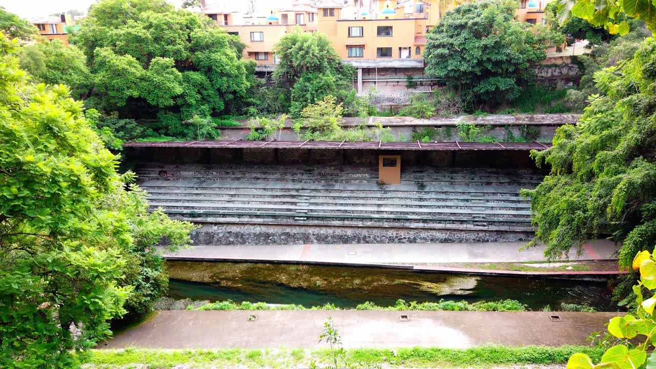 Slow pan left showing vibrant green tree leaves and a large stone stairway in Cuernavaca, Mexico.