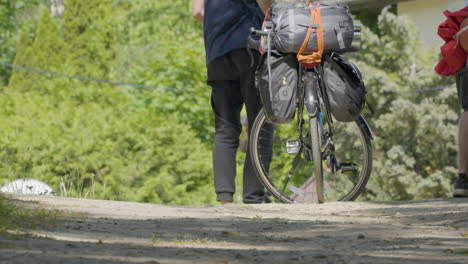 male standing beside touring cycle with pannier bags attached on rear wheel