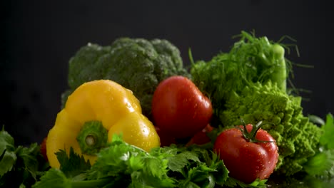 Tomato-falls-in-fresh-healthy-vegetable-pile,-water-splash,-slow-motion-studio