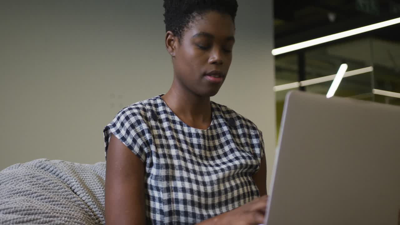 African american businesswoman sitting at desk using laptop in office