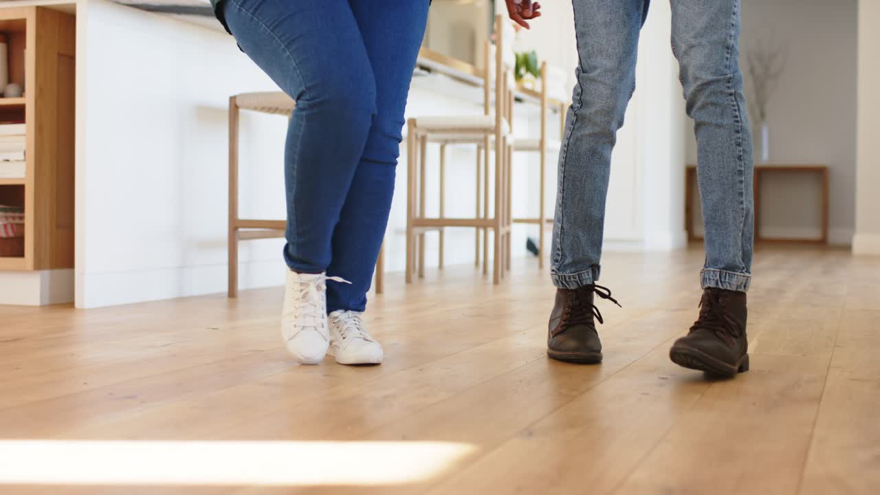 Diverse friends starting dance footwork with synced taps on floor in kitchen practicing routine
