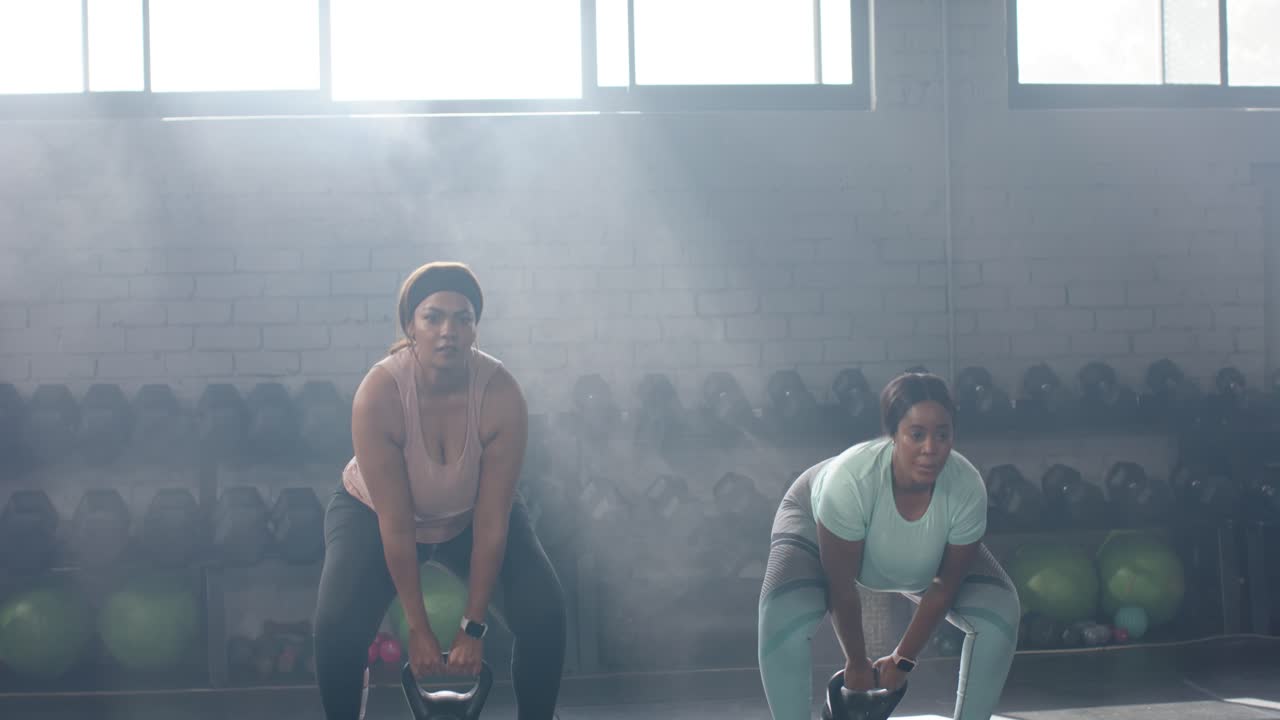 Dopo l'hip hinge, diverse partner di allenamento si allenano in palestra sollevando kettlebell per aumentare la forza