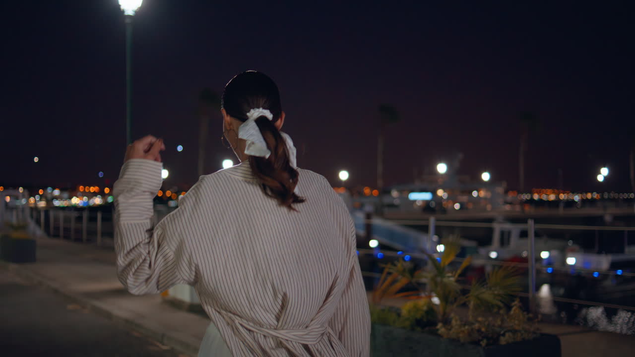 женщина, гуляющая по городскому причалу ночью.