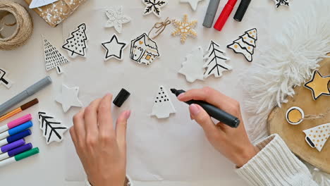 woman hand paints ornaments with christmas tree shape