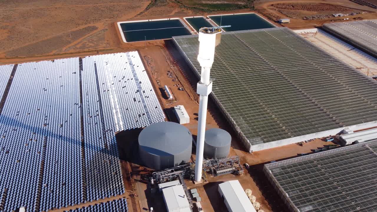 vista aérea de una granja solar térmica con heliostatos que concentran la luz solar en un receptor central, destacando la energía renovable y la generación de energía sostenible