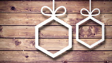 video composition with snow over christmas ornaments on wood