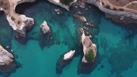 Hermosa-Formación-Rocosa-En-El-Mar-Mediterráneo-Con-Gente-Nadando-Desde-Arriba