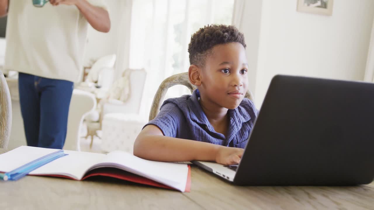 Happy african american boy using laptop for online lesson, in slow motion
