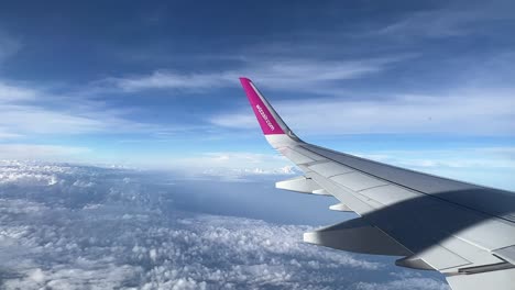 Wizz-Air-plane-wing-in-the-air-in-the-clouds-during-the-day-4K