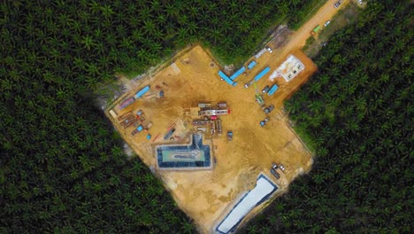 Cinematic-Drone-Footage-of-Onshore-Drilling-Rig-equipment-structure-for-oil-exploration-and-exploitation-in-the-middle-of-jungle-surrounded-by-palm-oil-trees-during-sunset-and-high-oil-price