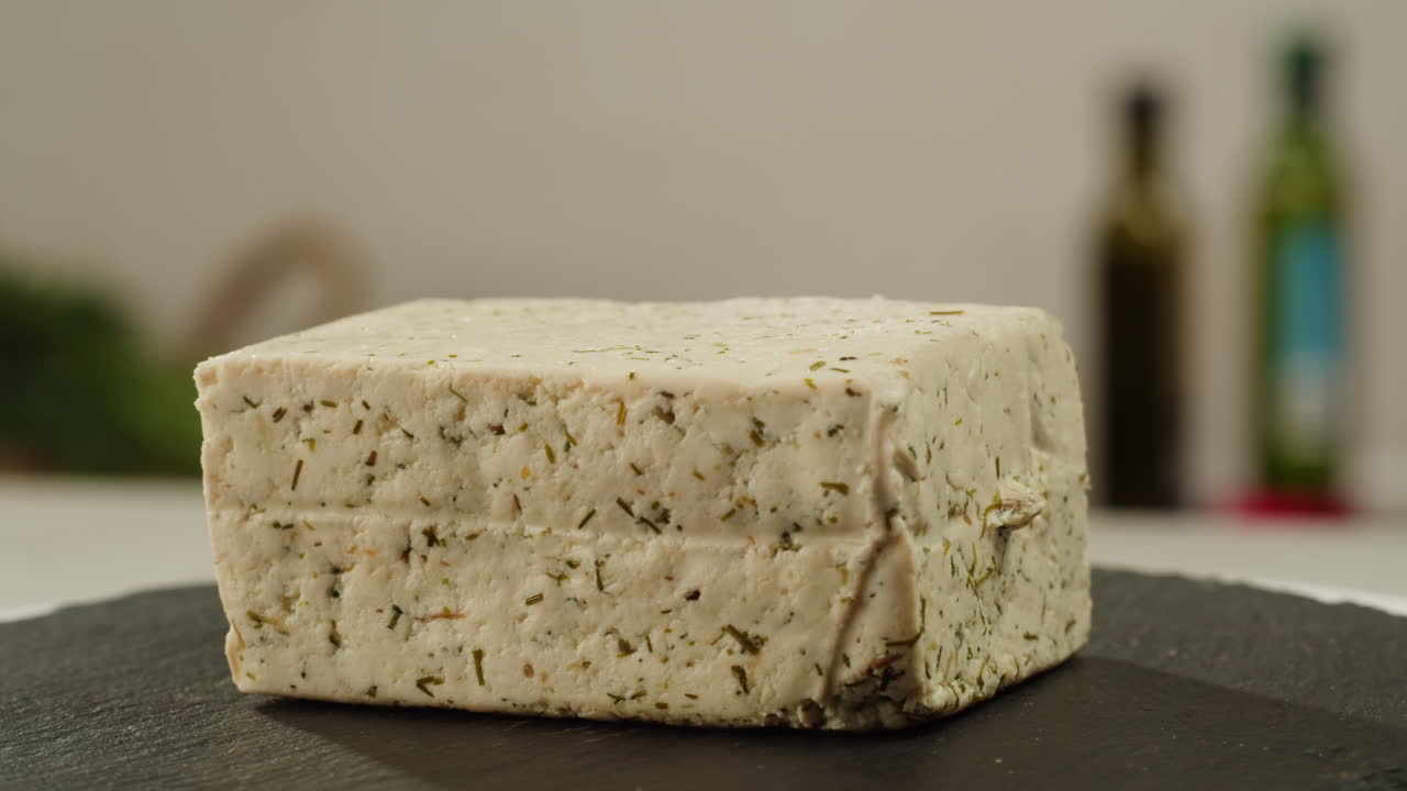 Chef cut cheese for Fried tofu with sesame seeds and spices on cast iron pan, cooking japanese salad. Healthy ingredient for cooking vegan vegetarian diet food. Roasted tofu over black background.