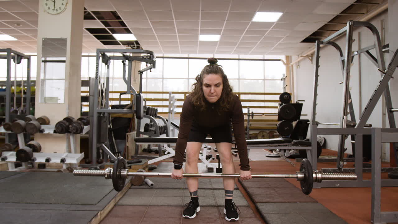Woman performing deadlift exercise in a gym