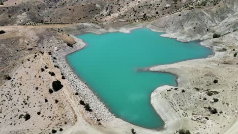 Drone-shooting-of-a-green-mountain-lake-against-the-backdrop-of-a-mountain-landscape-of-yellow-fields-and-natural-terraces-in-Turkey