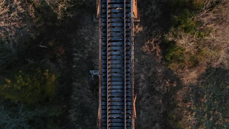 aerial top down shot moving along the tracks of the pope lick railroad trestle in louisville kentucky at sunset