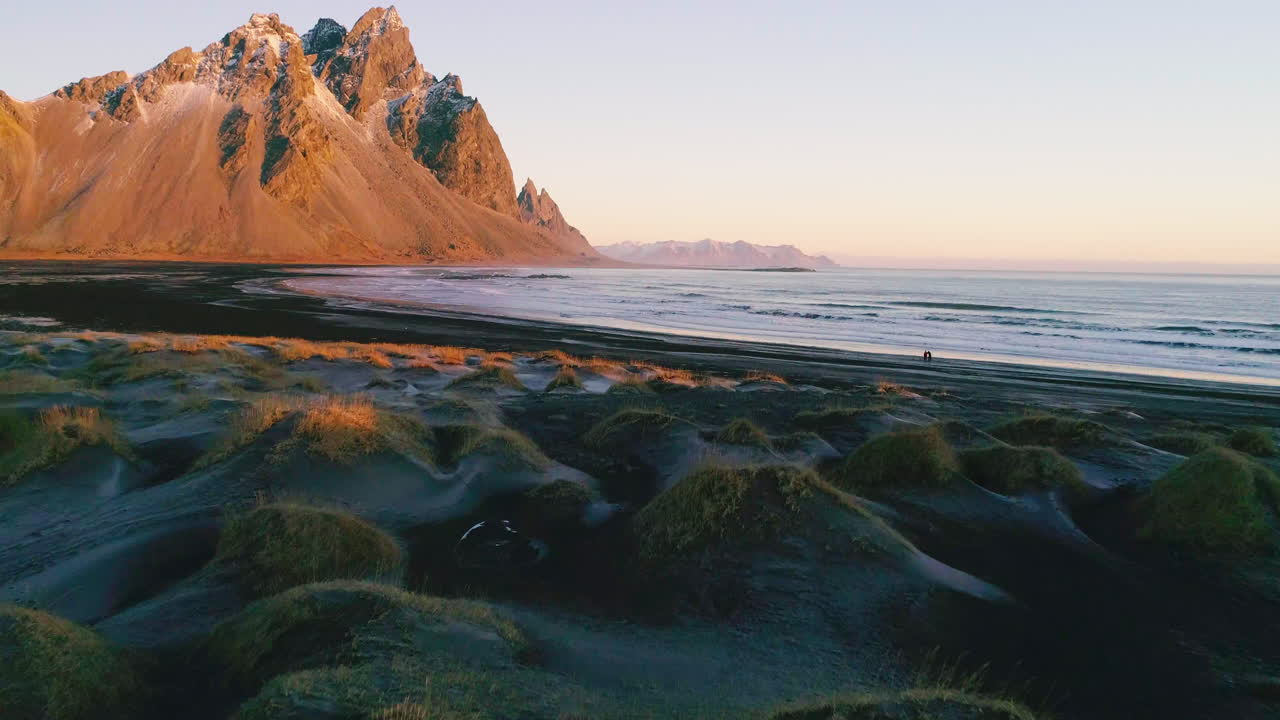 vista aérea a través de las dunas iluminadas por el sol de stokksnes y la playa de arena negra hacia la impresionante montaña vestrahorn