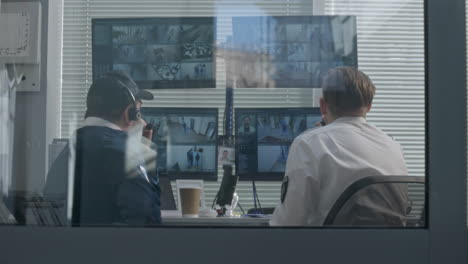 security guard monitoring surveillance cameras in control room
