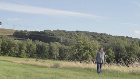 woman walks in countryside with a walking stick