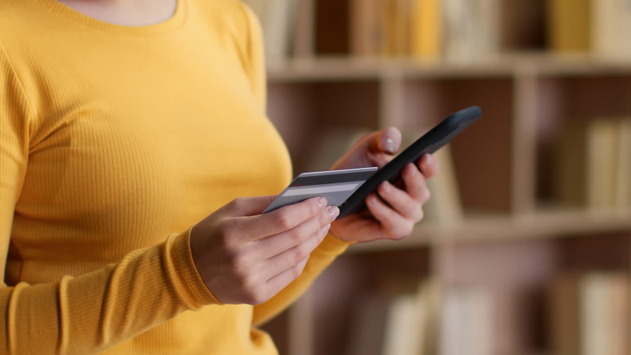 persona que realiza un pago en línea con una tarjeta de crédito y un teléfono inteligente