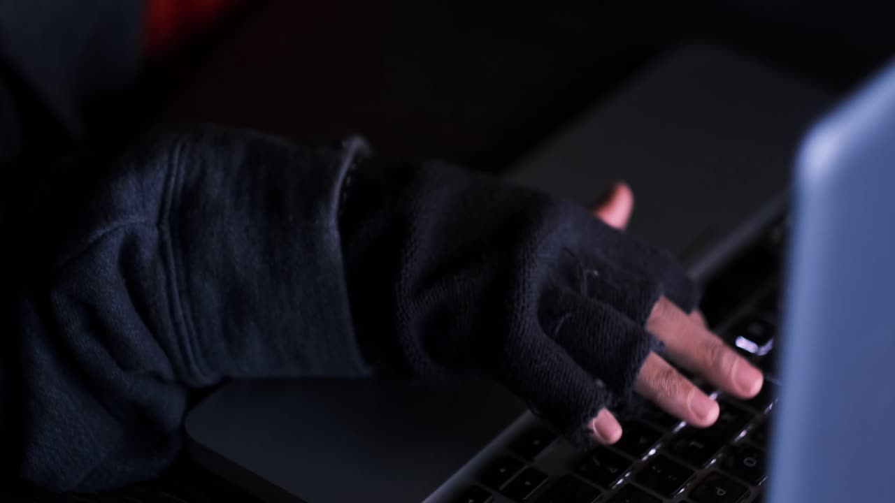 persona pirateando una computadora portátil por la noche