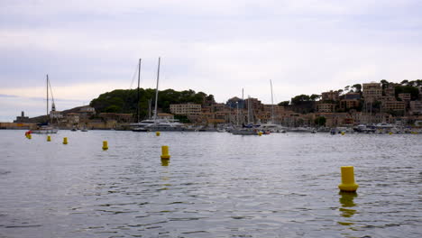 barcos en el pequeño puerto deportivo de port d'sóller, mallorca, con montañas y bosques al fondo