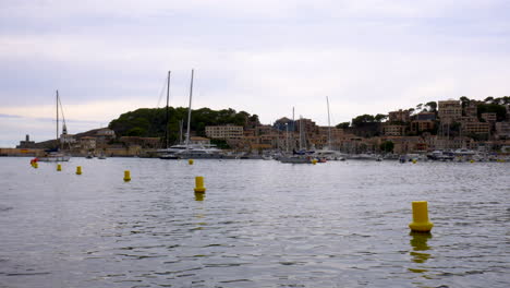 boats lying in the small marina of port d’sóller, mallorca, with mountains and forest in the background