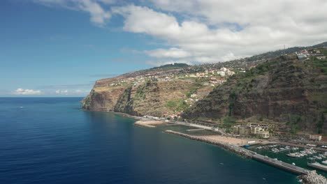 sunny day at calheta shore with cliffs on madeira island with man made beach