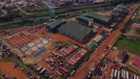drone flying to a large factory next to a factory with smoking chimneys in ibadan, nigeria. african production company of local home based raw materials.