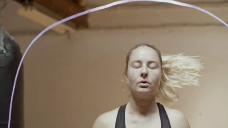 Front-view-of-focused-Caucasian-woman-jumping-rope-in-gym