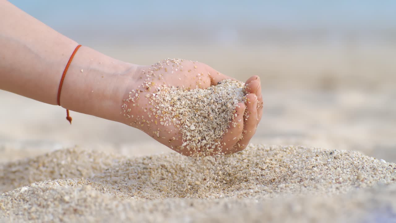 Sand falling from hand in slow motion on a beach. Vacation and travel concept. Shot on super slow motion camera 1000 fps