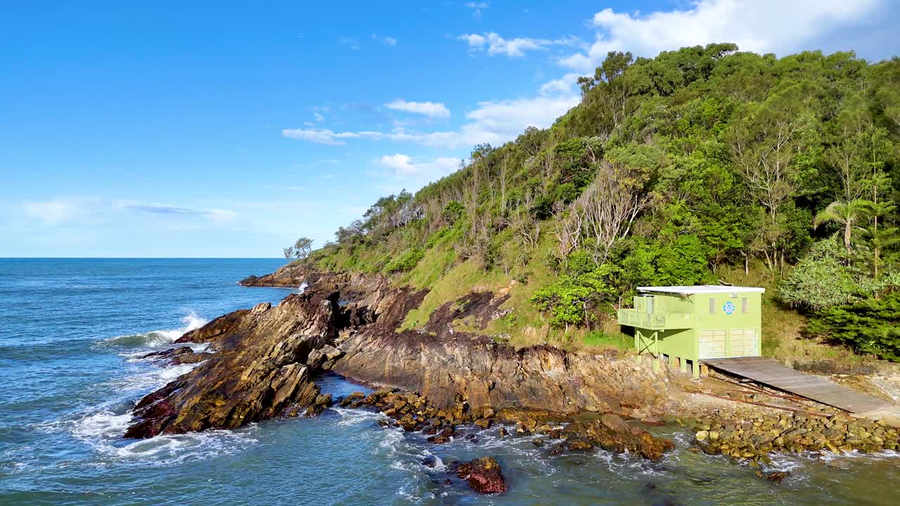 Aerial view of rugged coastline with waves crashing against rocks under bright daylight at Charlesworth Bay Beach, Coffs Harbour