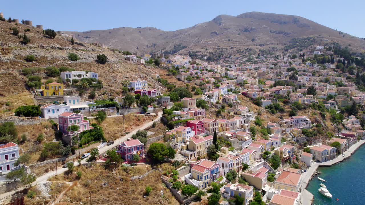 Drone view of colorful houses on a Greek island, highlighting vibrant coastal scenery