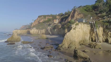 Aerial-shots-of-El-Matador-beach-over-breaking-waves-and-rocks-on-a-hazy-summer-morning-in-Malibu,-California